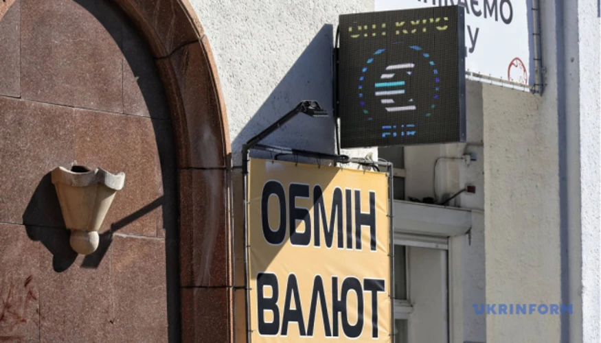 Символи долара США та євро на тлі будівлі Національного банку України